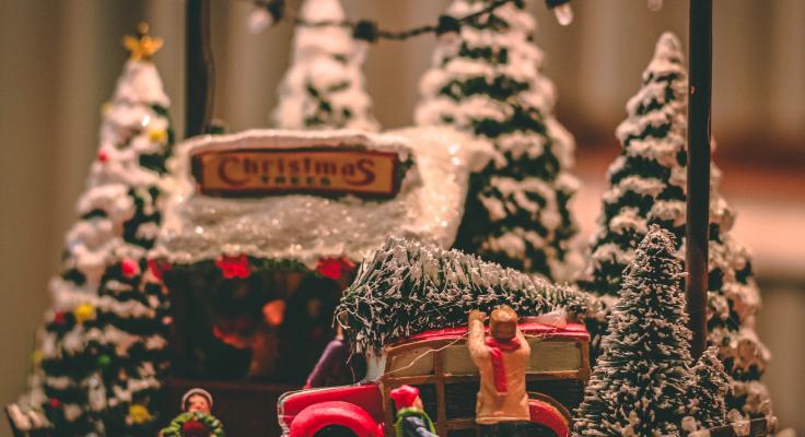 modelfiguurtjes uit een kerstdorp die een kerstboom op een auto binden